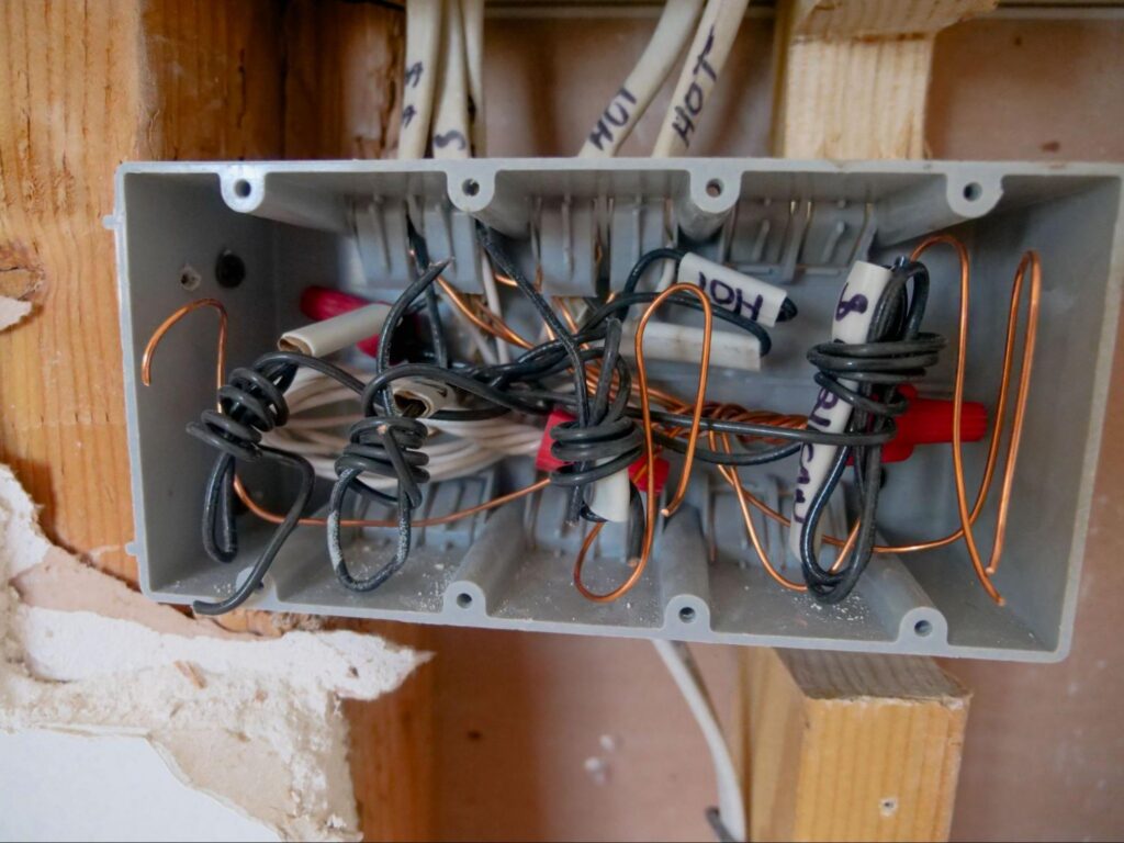Tangled wiring in an open four-gang switch box awaiting residential electrical repair in Marshfield, MA.